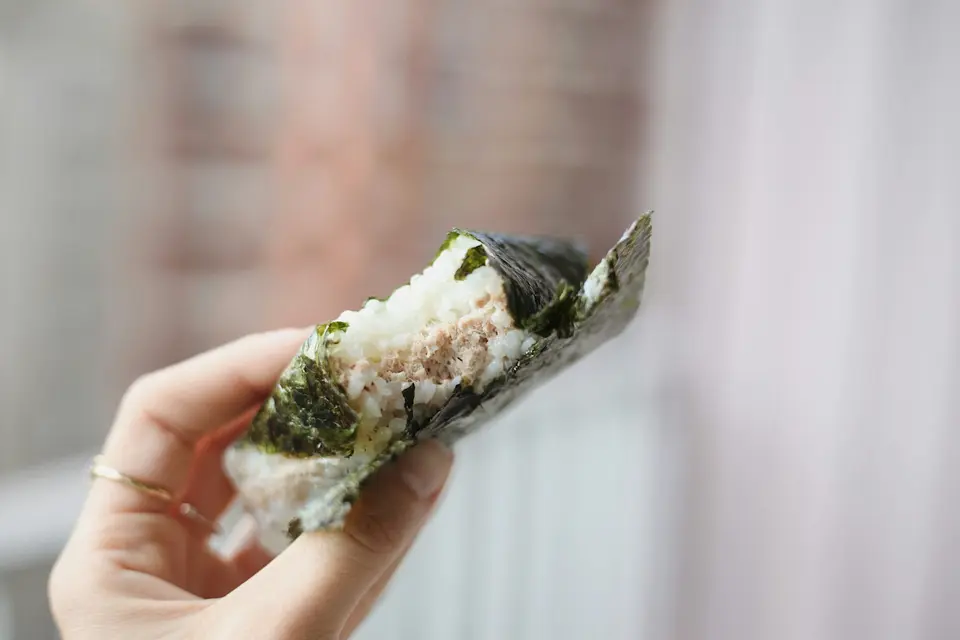 Onigiri med lax som hålls i handen